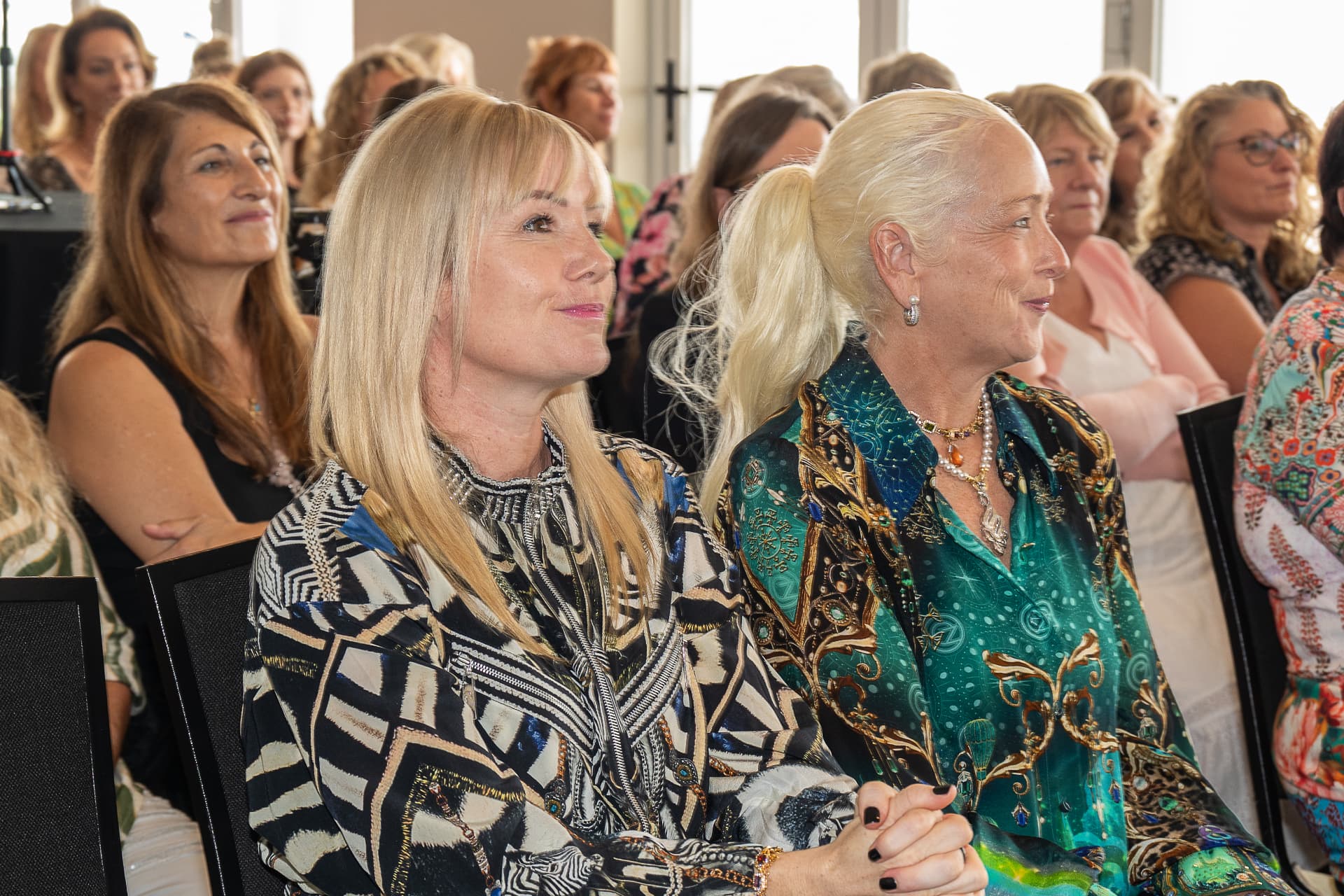 Two women in the front row listening to a speaker